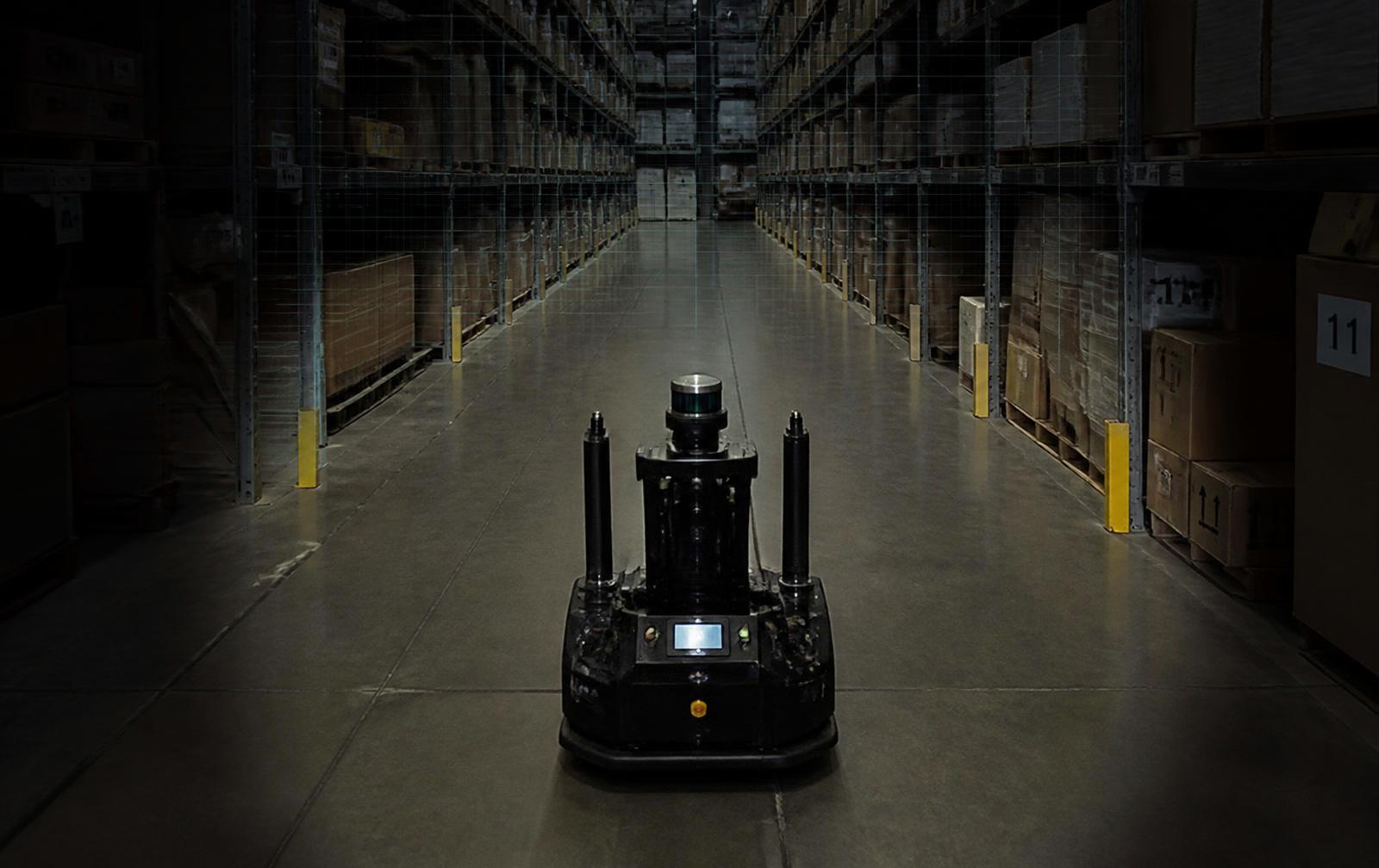 A sensor-equipped mobile robot operating in a dimly lit warehouse aisle